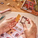 A person assembles a little piece of furniture from the Robotime A-Frame Cabin