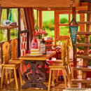 The cozy dining area with wooden chairs and a set wooden table in the Robotime A-Frame Cabin