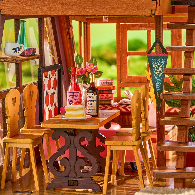 The cozy dining area with wooden chairs and a set wooden table in the Robotime A-Frame Cabin