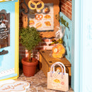 Wrapped cake, a plant, bag, and sign with menu in the Robotime Fluffy Cat Bakery