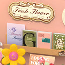 Close-up of the nameplate and books about flowers in the Robotime Fresh Flower Shop 
