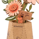 Details of a flower and vase with a small sign of the Robotime Light Orange Gerbera