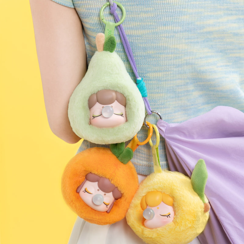 Pear, Orange, and Lemon variants of the Robotime Nanci Fruit Mood Surprise Plush Pendant blind box series, hanging from a bag
